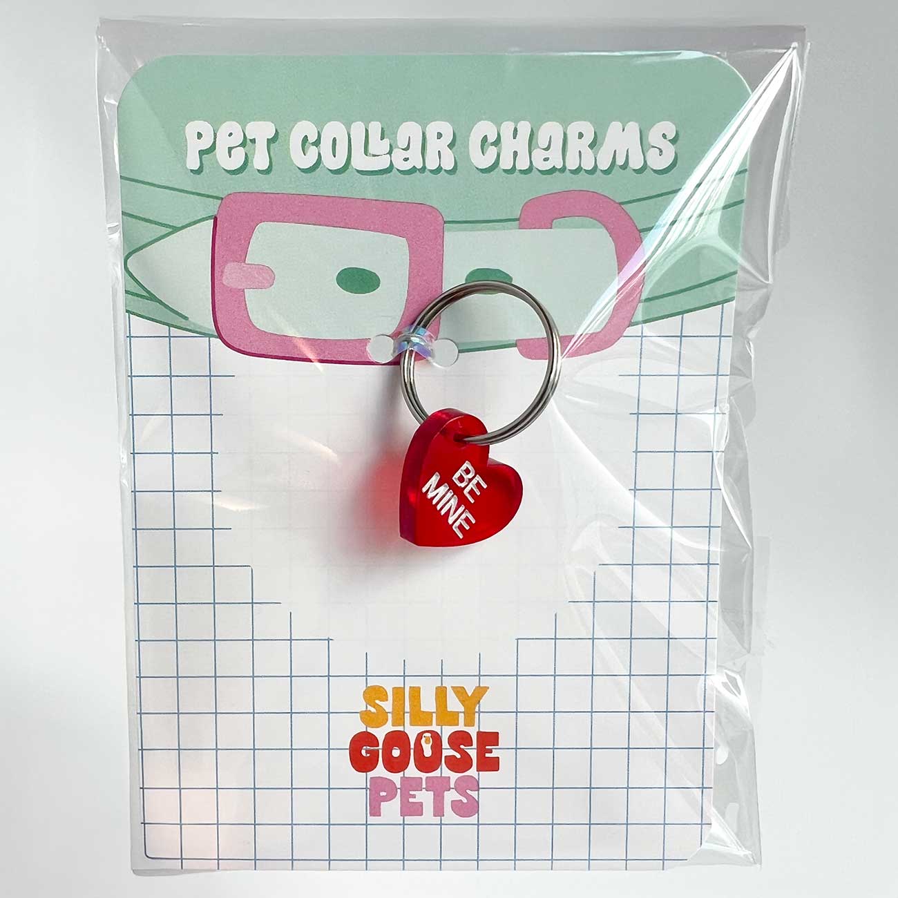 Red heart-shaped pet collar charm with 'Be Mine' text in a clear package labeled 'Pet Collar Charms' by Silly Goose Pets.