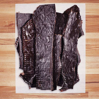 Beef heart dog treat on a white paper with a wooden surface background