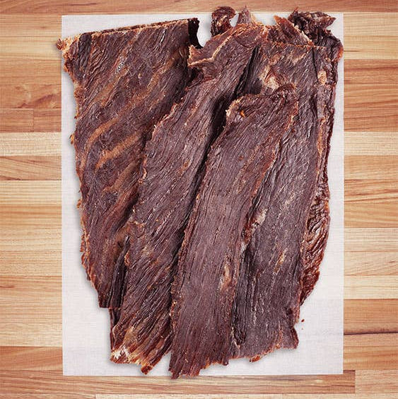 Dried beef jerky on a white parchment paper on a wooden surface