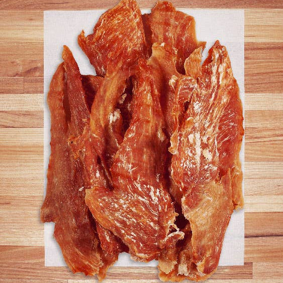 Dried chicken jerky strips on a wooden surface
