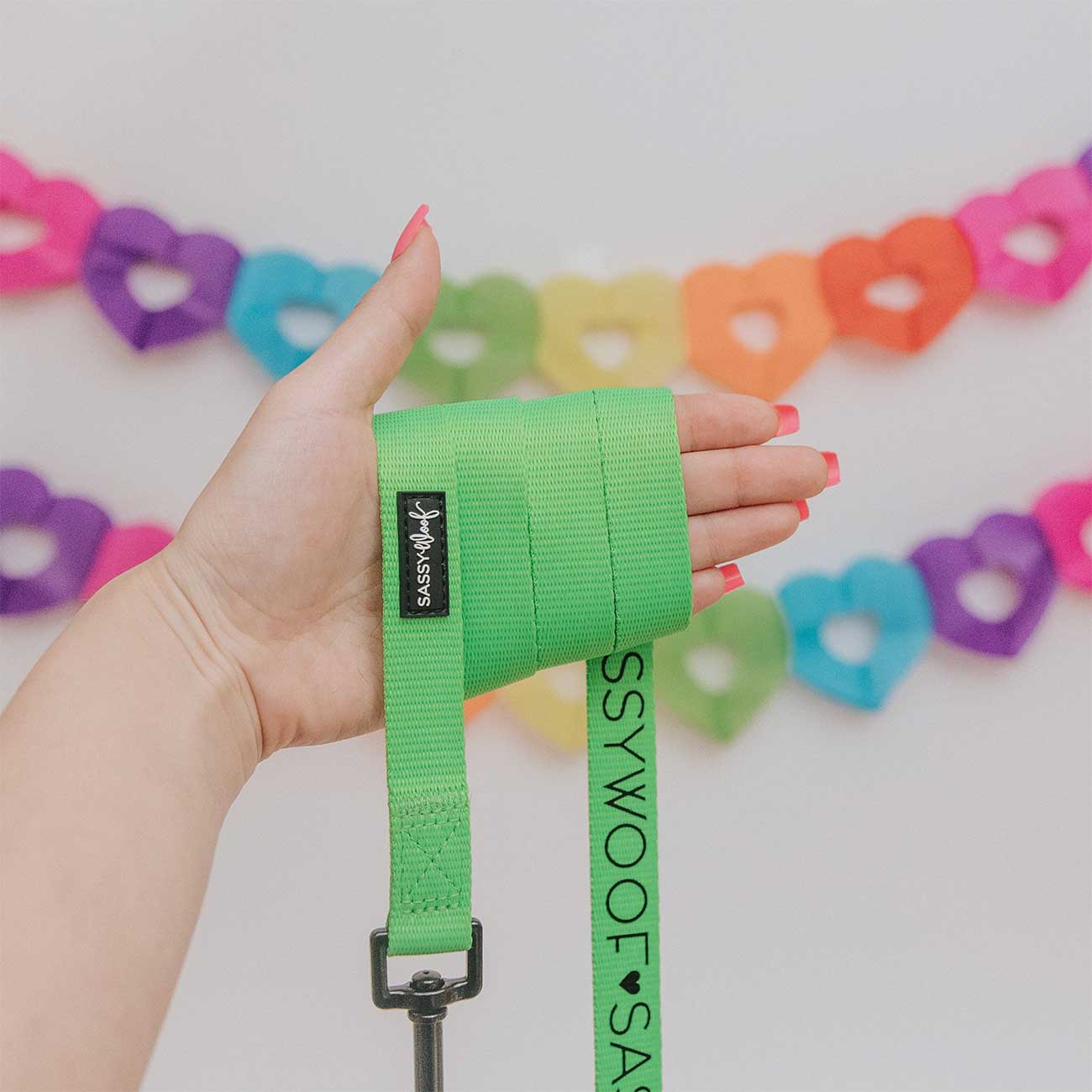 Hand wearing a green wrist wrap with a colorful heart-shaped background