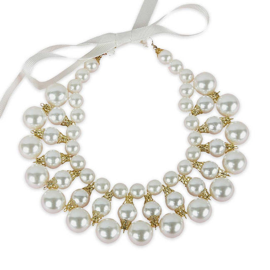 Dog pearl necklace with gold accents and a white ribbon on a white background