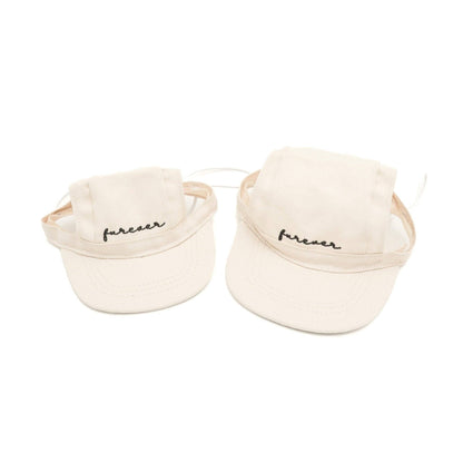 Two cream-colored baseball caps with 'furever' text on a white background