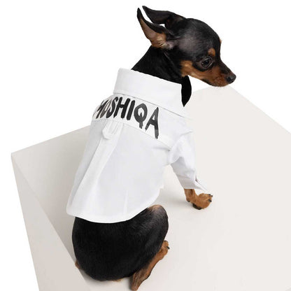Small dog wearing a white outfit with 'MUSHIQA' text on a white background