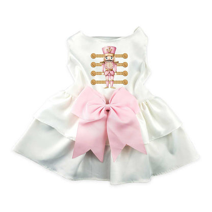 White dog dress with pink bow and cartoon nutcracker on a white background