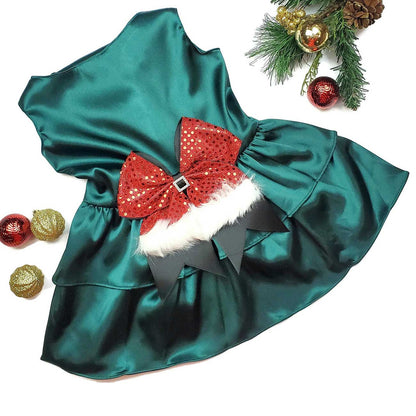 Green satin dog dress with a red sequin bow on a white background with Christmas decorations.