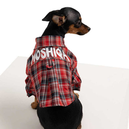 Dog wearing a red plaid shirt with 'MOSHIQA' printed on it, sitting on a white surface.