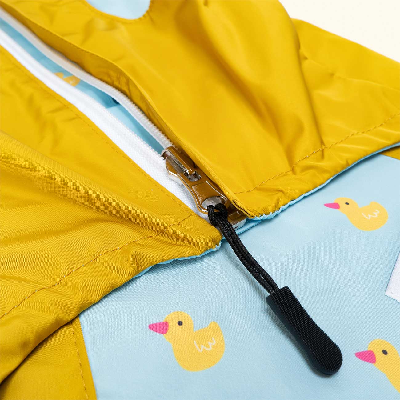 Close-up of a yellow dog jacket with a blue interior featuring duck illustrations.