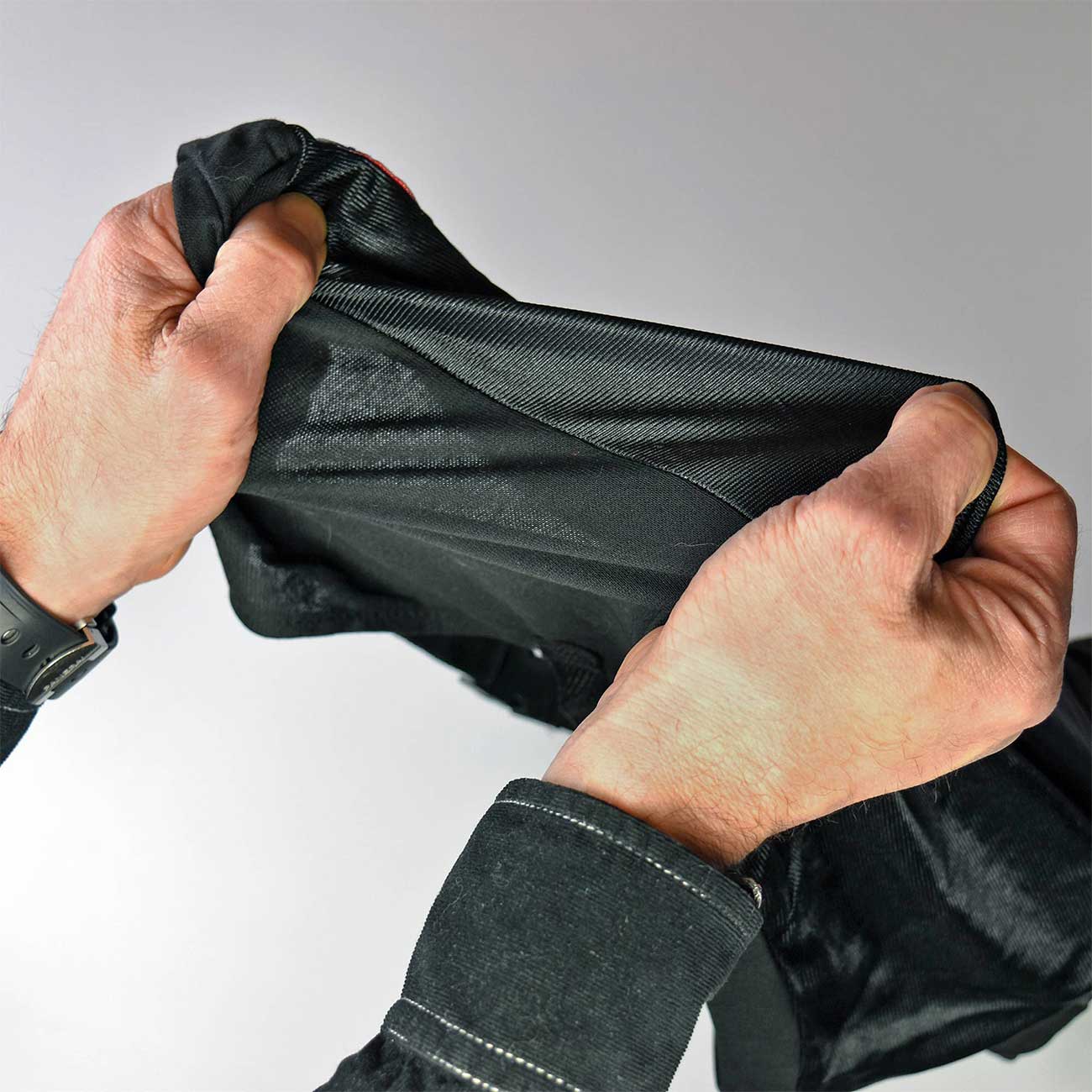 Person holding a black jacket against a white background