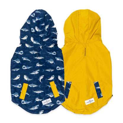 Two hooded dog vests, one blue with whale pattern and one yellow showcasing the reverseable feature, on a white background.