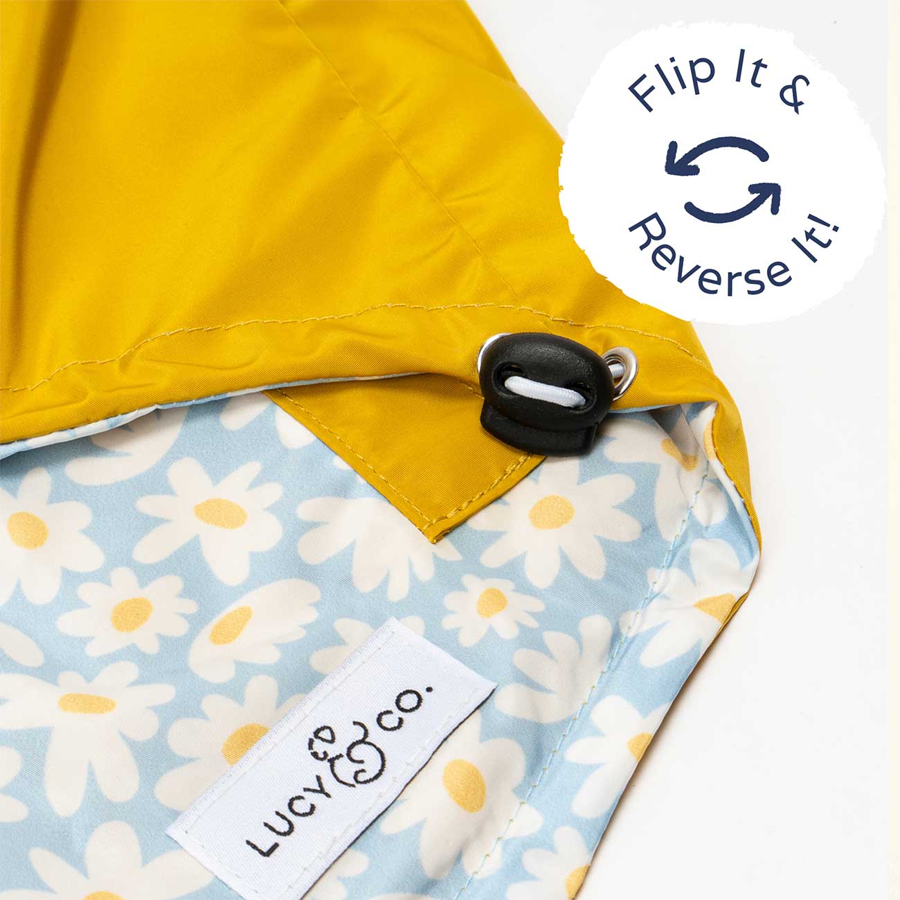 Reversible raincoat with yellow exterior and floral interior, featuring a 'Flip It & Reverse It!' label and a visible brand logo.