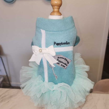 Turquoise dog dress with white bow and ruffles on a mannequin against a neutral background